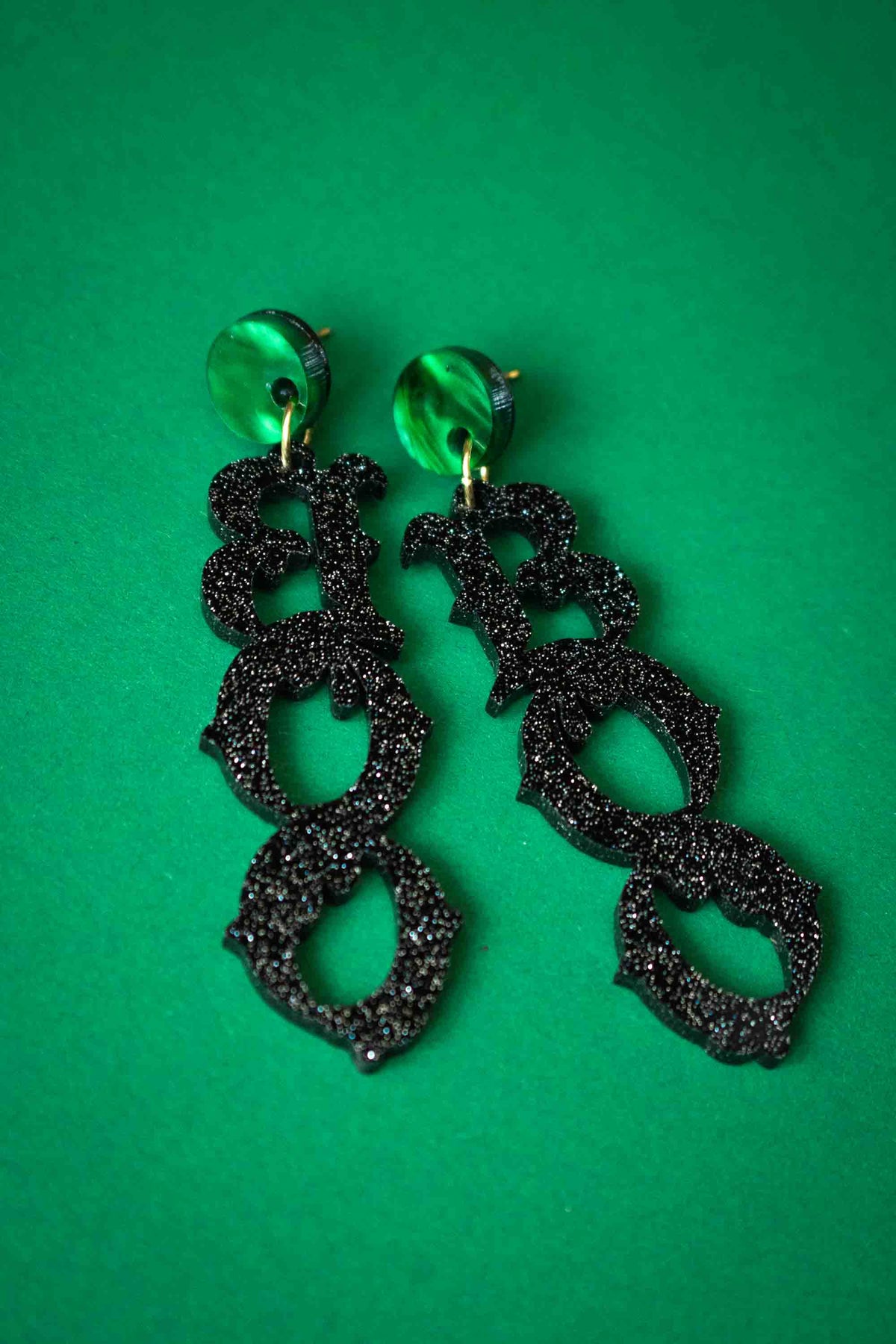 Boucles d’oreilles BOO noires pailletées sur fond vert