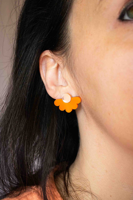 Gros plan sur l'oreille avec une puce fleur orange acrylique miroir doré portée, bijou fait main Limonade Studio