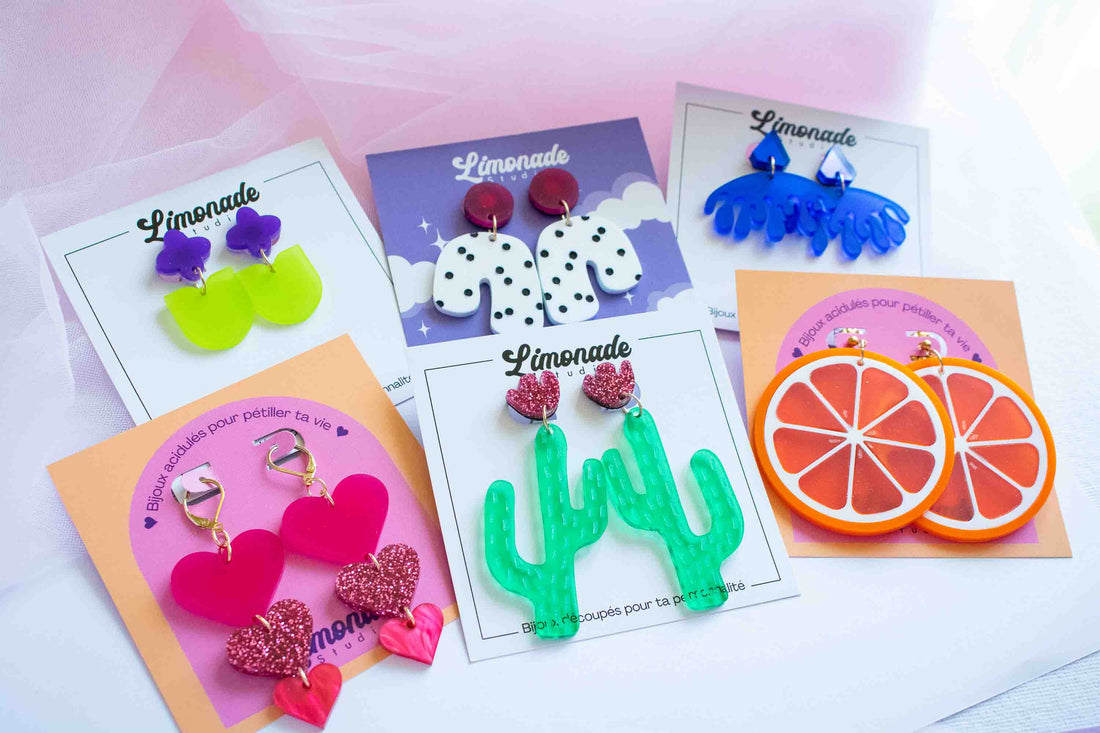 Assortiment de boucles d'oreilles acryliques colorées Limonade Studio — cactus vert, tranche d'orange, cœurs roses et vagues bleues sur cartes de présentation