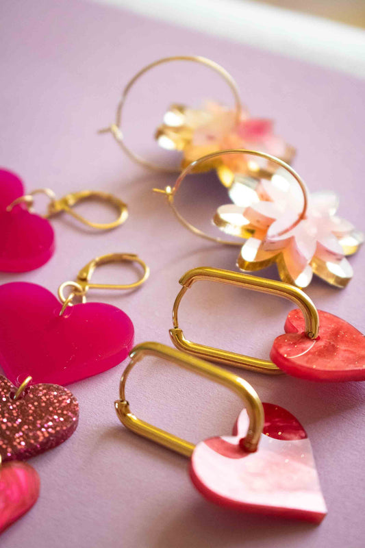 Gros plan sur les apprêts dorés de boucles d'oreilles acryliques cœur roses Limonade Studio — détail des dormeuses et crochets plaqué or pour bijoux de qualité
