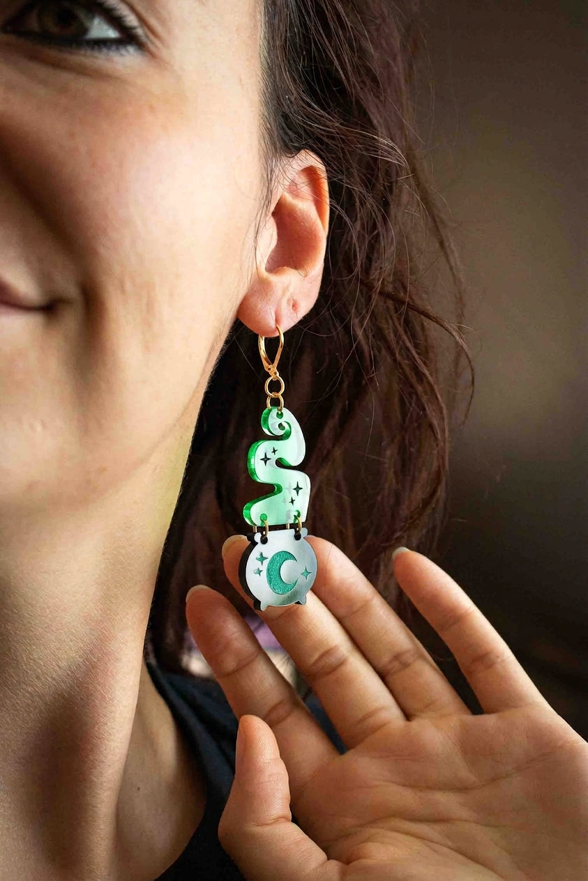 Boucle d’oreille chaudron noir avec fumée verte portée de face par une femme
