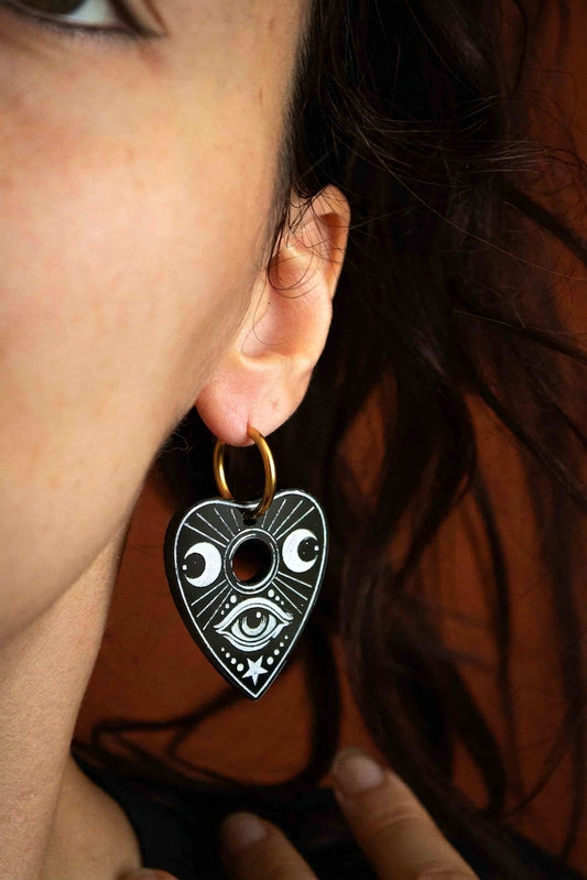Vue rapprochée d’une boucle Ouija noire et blanche portée près du visage