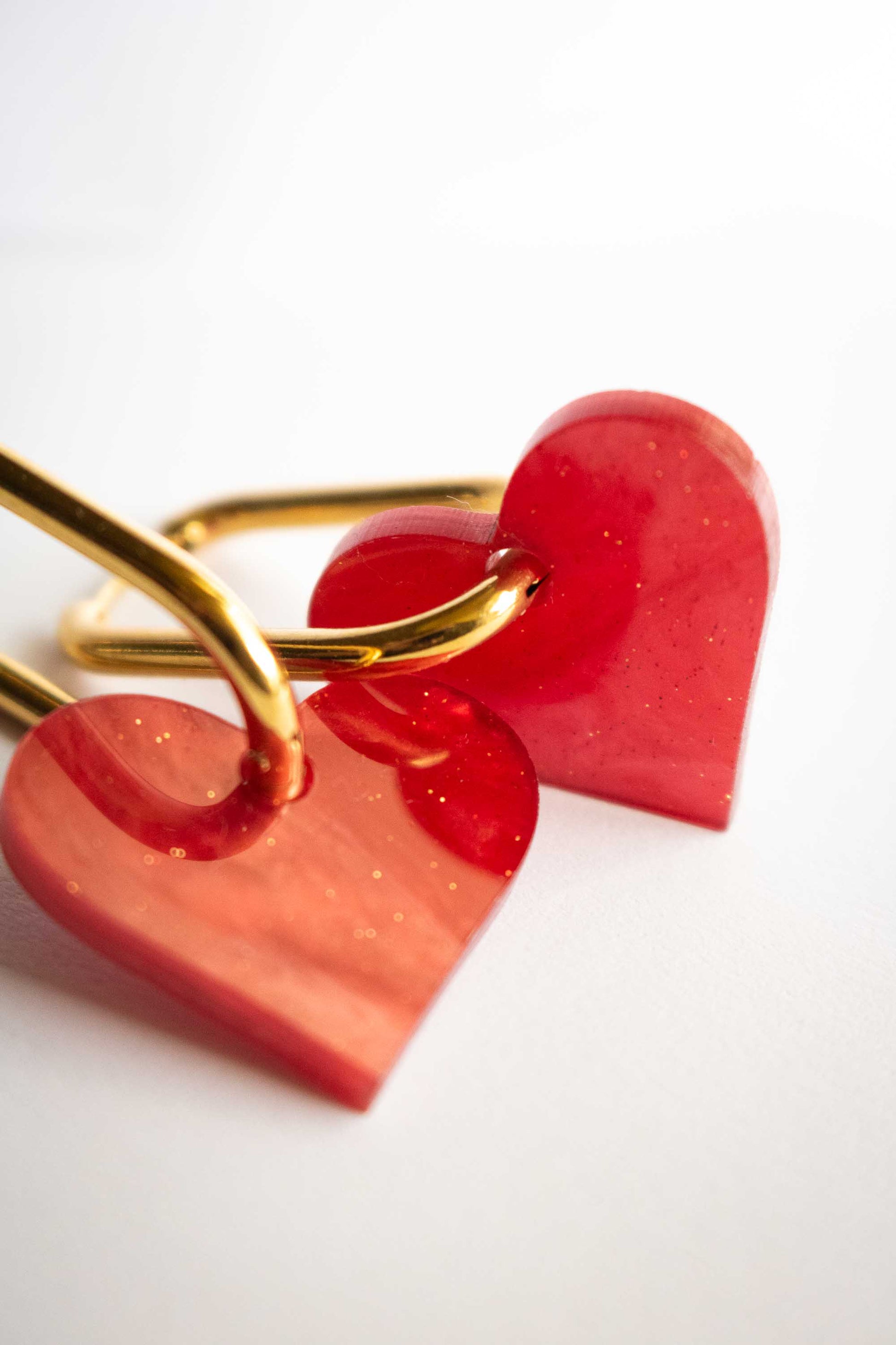 Gros plan sur boucles cœur rouge acrylique marbré pailleté, texture dorée visible, bijou fantaisie fait main découpé au laser par Limonade Studio