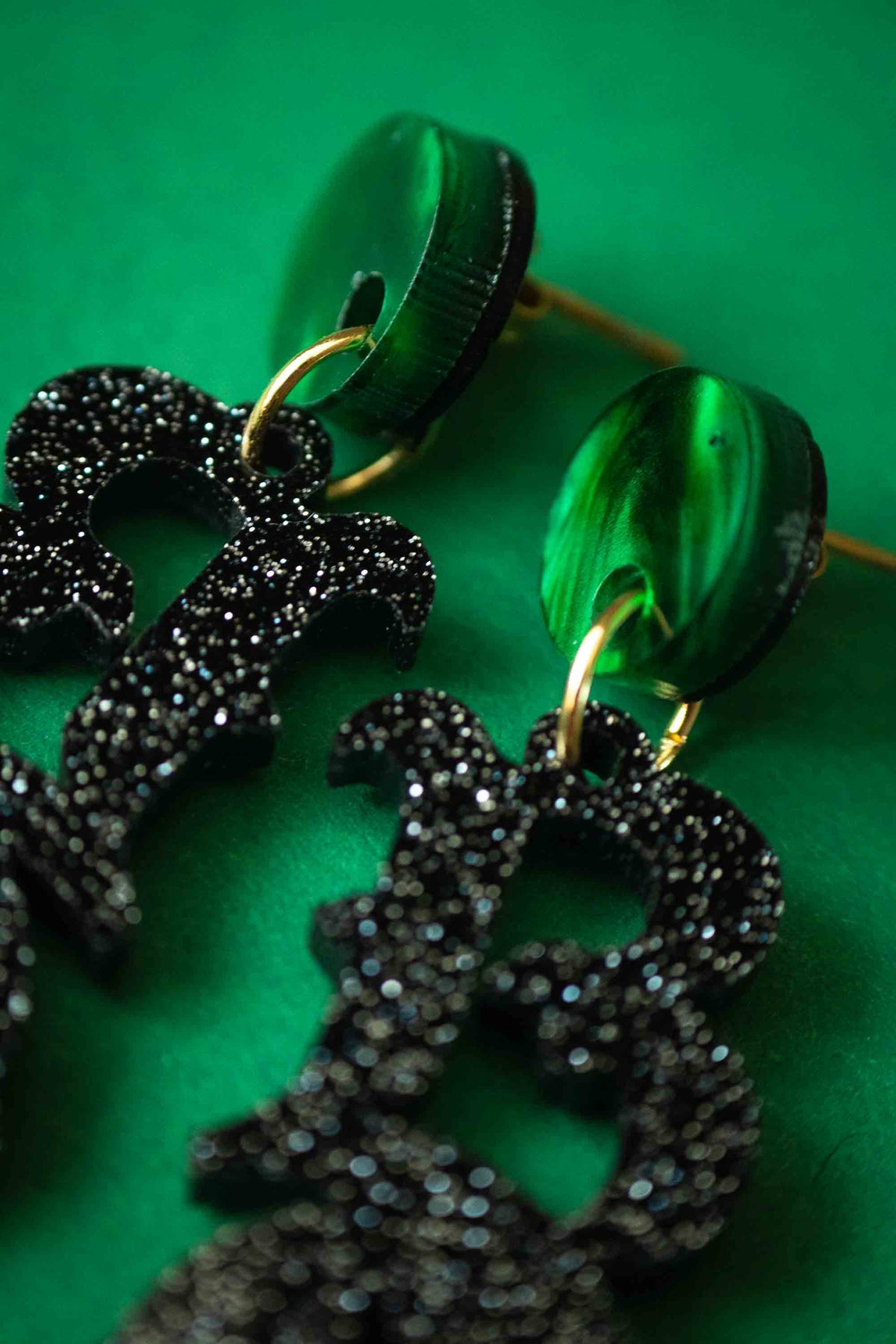 Détail des paillettes noires et des puces vertes des boucles BOO