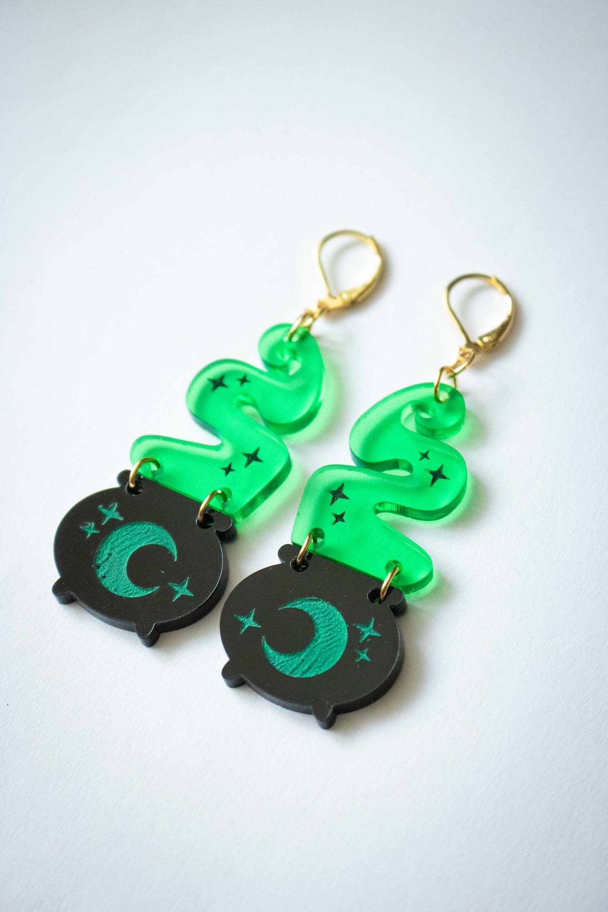 Vue inclinée des boucles d’oreilles chaudron noir, lune verte et fumée translucide