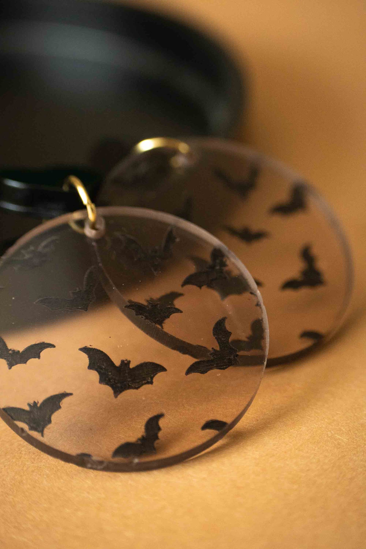 Détail du motif chauves-souris noires sur un pendentif rond marron transparent