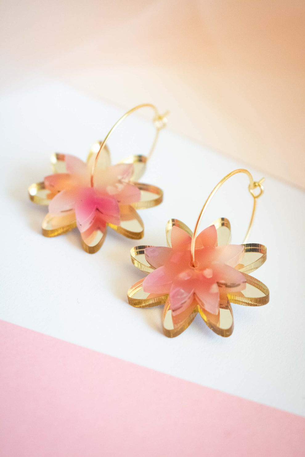 Boucles d'oreilles fleur en acrylique miroir doré et rose translucide, créoles acier inoxydable plaqué or 18 carats. Bijou unique signé Limonade Studio.