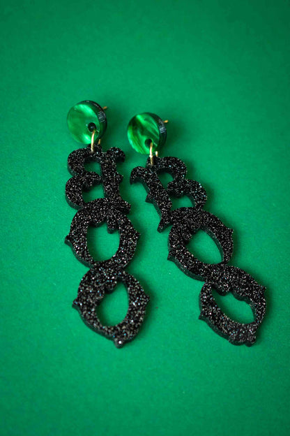 Boucles d’oreilles BOO noires pailletées sur fond vert