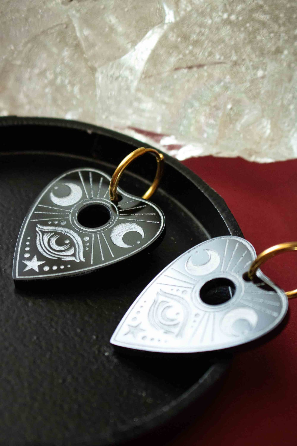 Paire de planchettes Ouija noires et blanches posée sur un plateau sombre