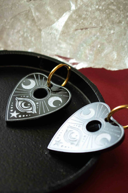 Paire de planchettes Ouija noires et blanches posée sur un plateau sombre