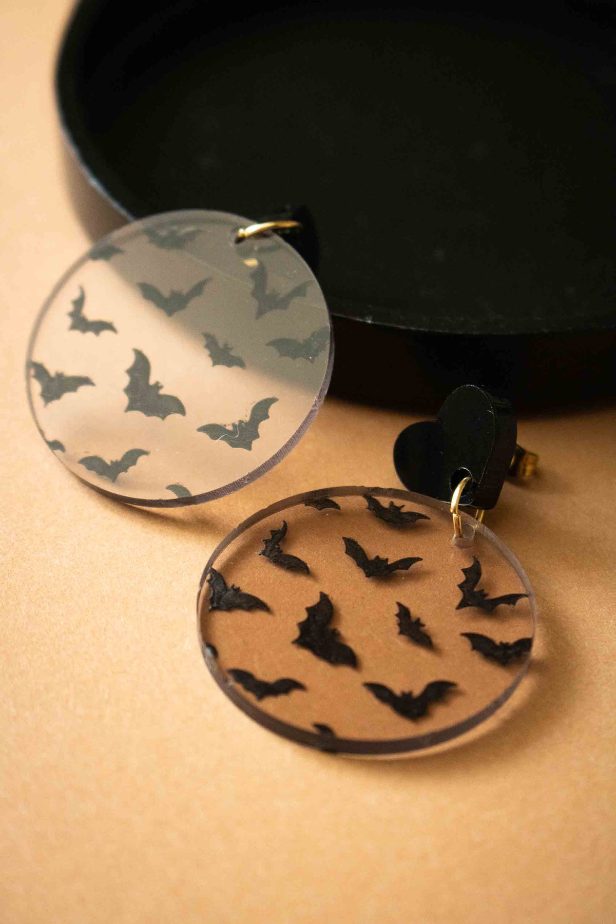 Boucles d’oreilles chauves-souris transparentes présentées mise en scène posée dans coupelle