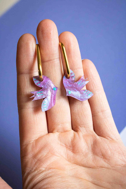 Boucles d'oreilles huggies oiseau violet acrylique légères, cadeau femme bijou fantaisie fait main Limonade Studio, portées en main paume ouverte