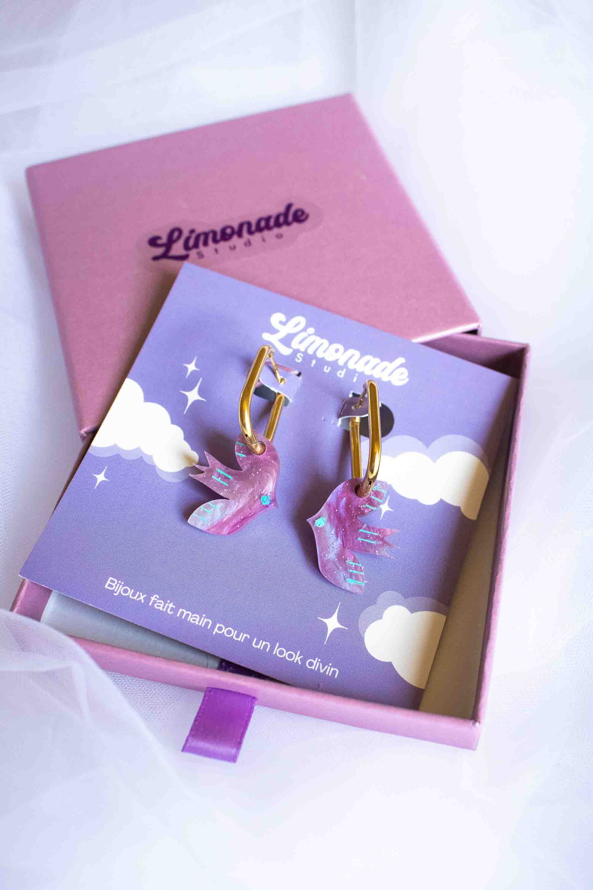 Paire de boucles d'oreilles oiseau violet découpé laser, packaging cadeau femme Limonade Studio, dans boîte violette avec ruban, sur cartonnette