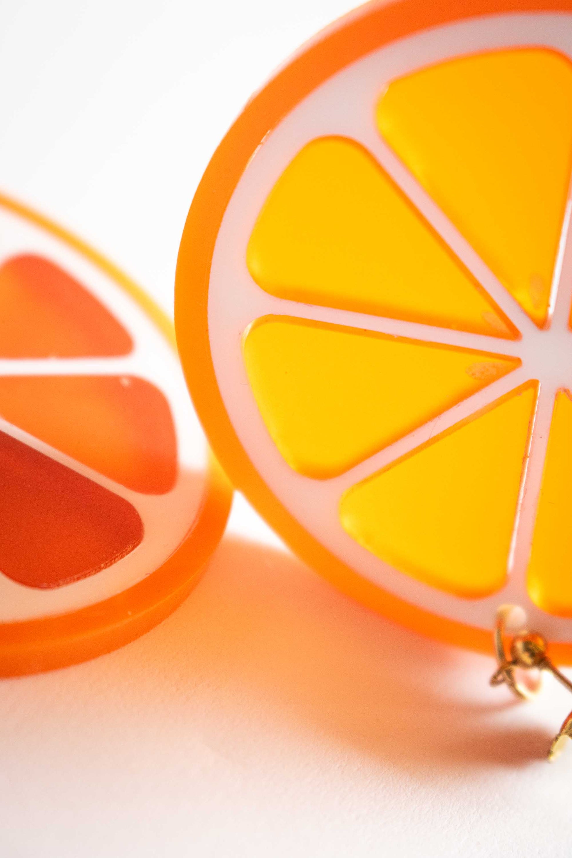 Gros plan sur boucles d'oreilles orange en acrylique découpé au laser, détail découpe et transparence, bijou créateur fait main, Limonade Studio