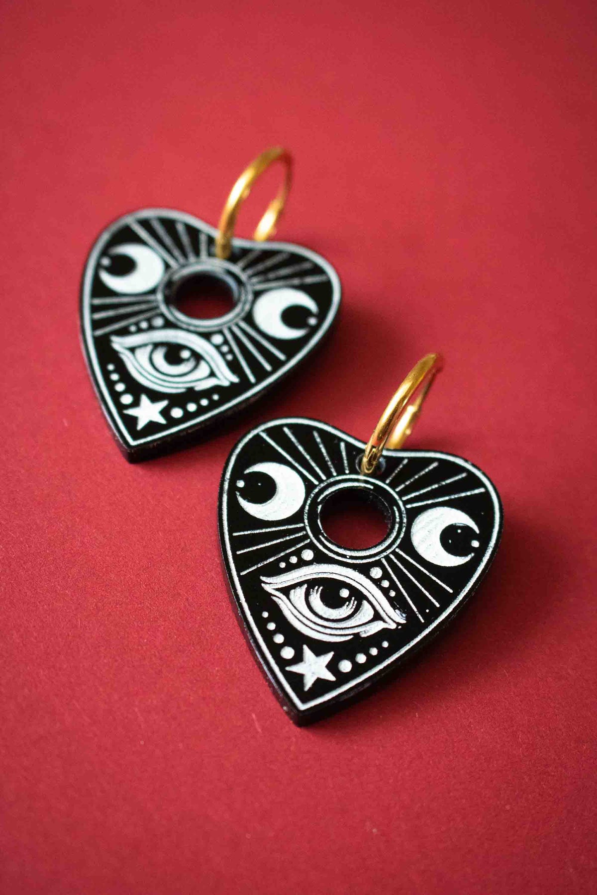 Gros plan de deux planchettes Ouija noires gravées d’un œil, de lunes et d’une étoile