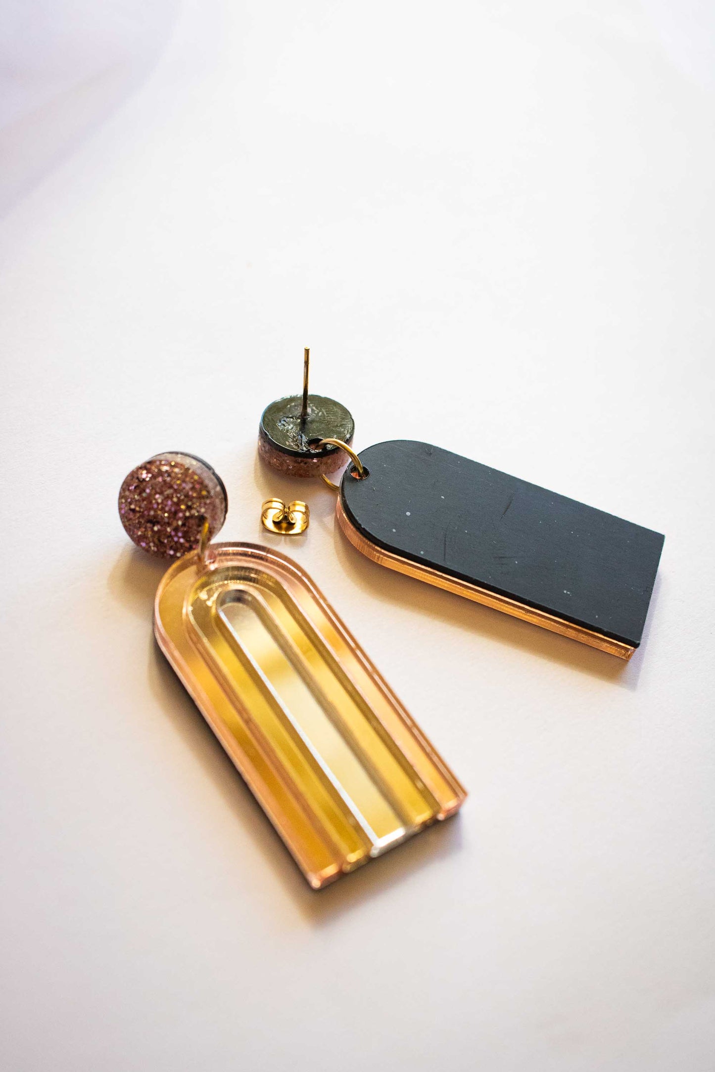 Détail dos et construction des boucles d'oreilles pendantes arche or miroir, acrylique découpé au laser, clou acier inox plaqué or, artisanal Limonade Studio