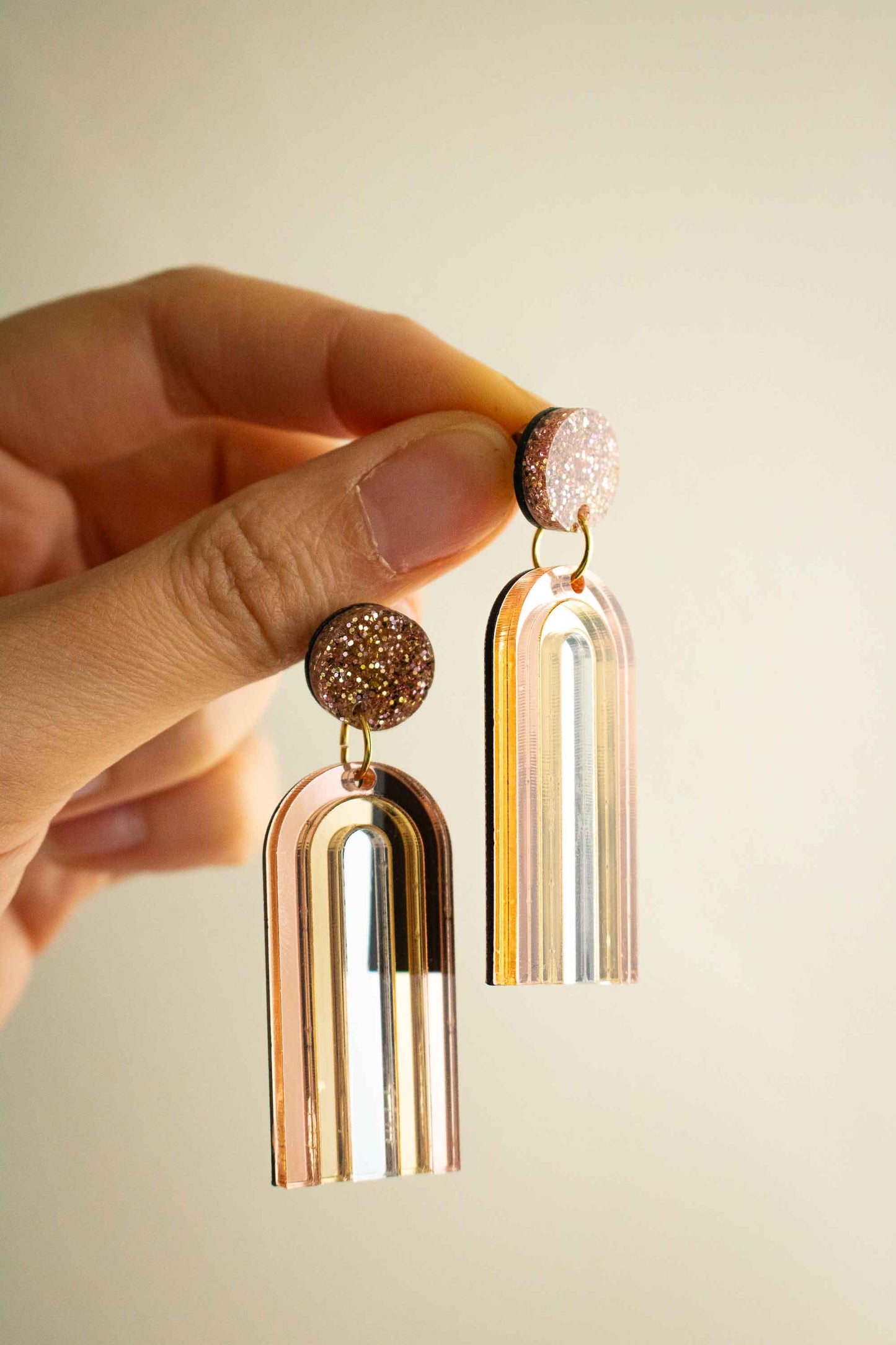 Boucles d'oreilles pendantes arche or rose miroir en acrylique découpé au laser, cadeau original artisanal, Limonade Studio, tenues en main avec reflets