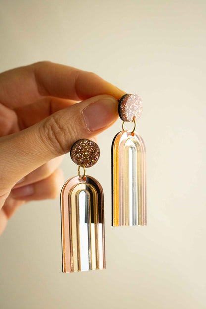 Boucles d'oreilles pendantes arche or rose miroir en acrylique découpé au laser, cadeau original artisanal, Limonade Studio, tenues en main avec reflets
