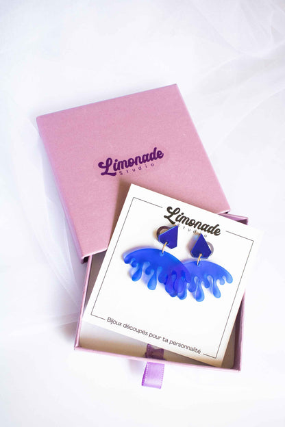 Boucles d'oreilles pendantes bleues bijou fantaisie acrylique dépoli, fait main découpe laser, Limonade Studio, dans boîte cadeau violette ouverte