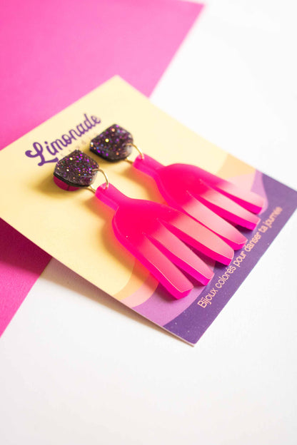 Boucles d'oreilles pendantes fuchsia acrylique laser sur cartonnette Limonade Studio, fond bicolore rose et blanc, cadrage serré
