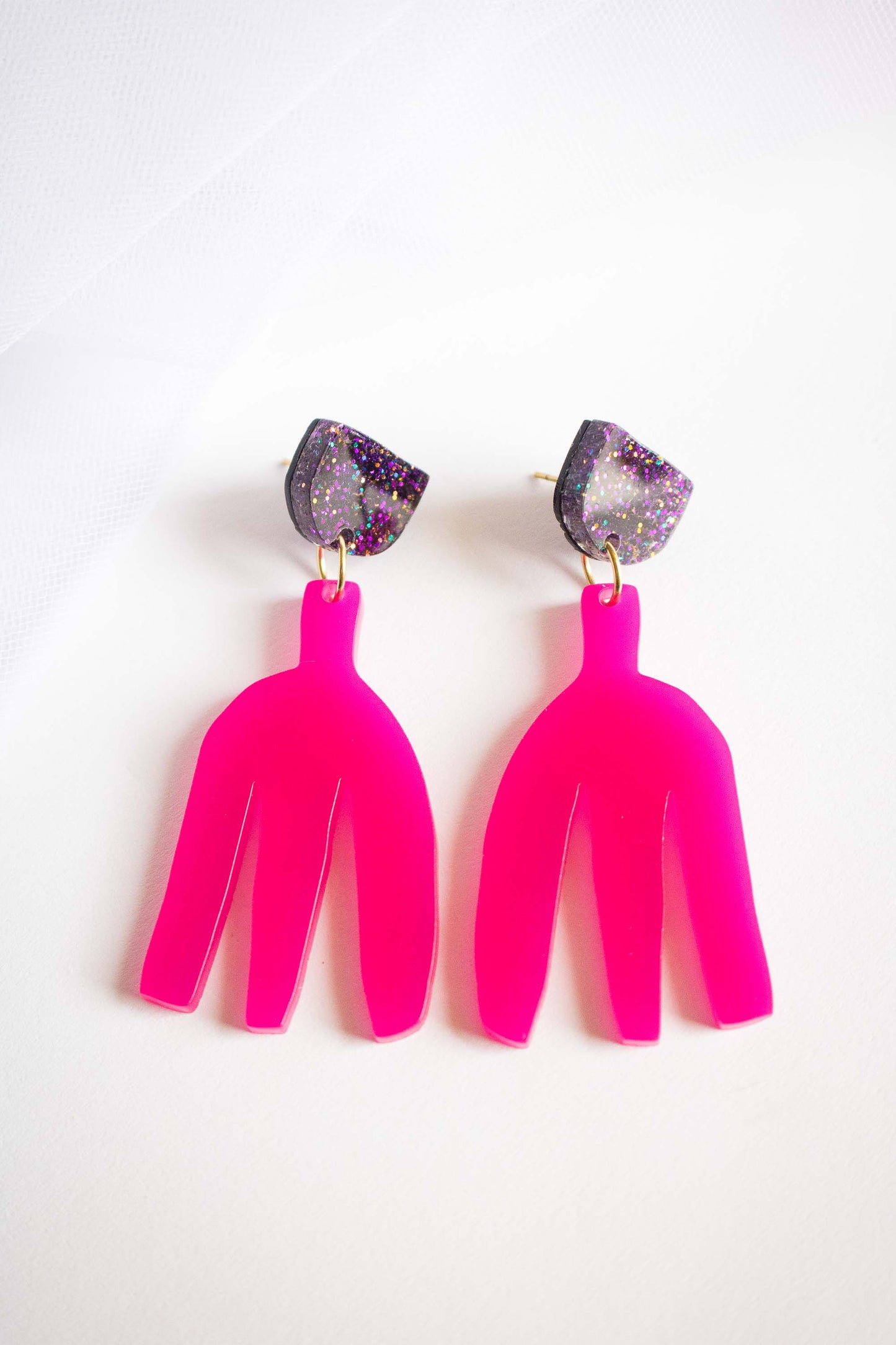 Boucles d'oreilles pendantes rose fuchsia en acrylique découpé au laser, clou demi-cercle pailleté holographique, fond blanc, bijoux faits main Limonade Studio