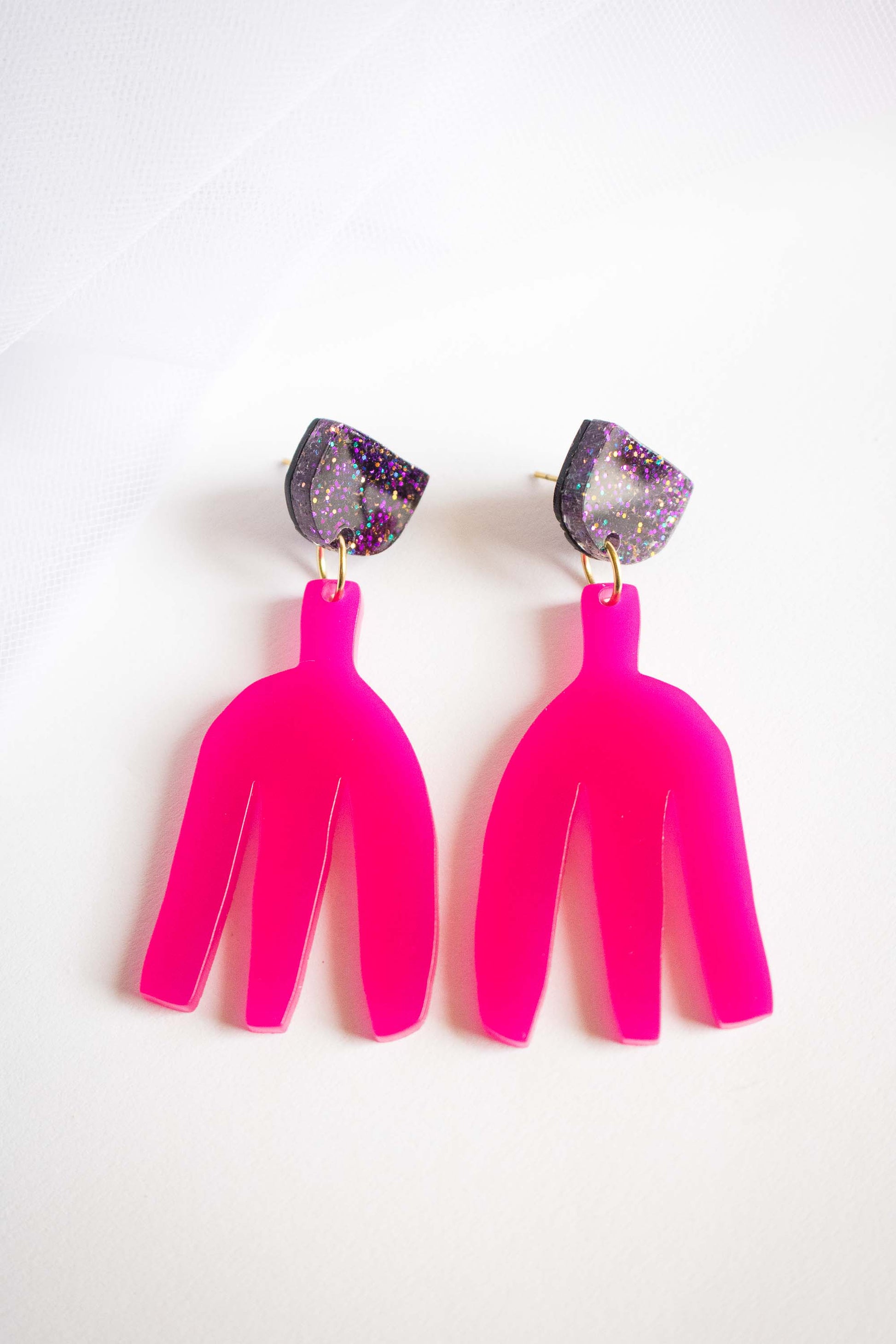 Boucles d'oreilles pendantes rose fuchsia en acrylique découpé au laser, clou demi-cercle pailleté holographique, fond blanc, bijoux faits main Limonade Studio