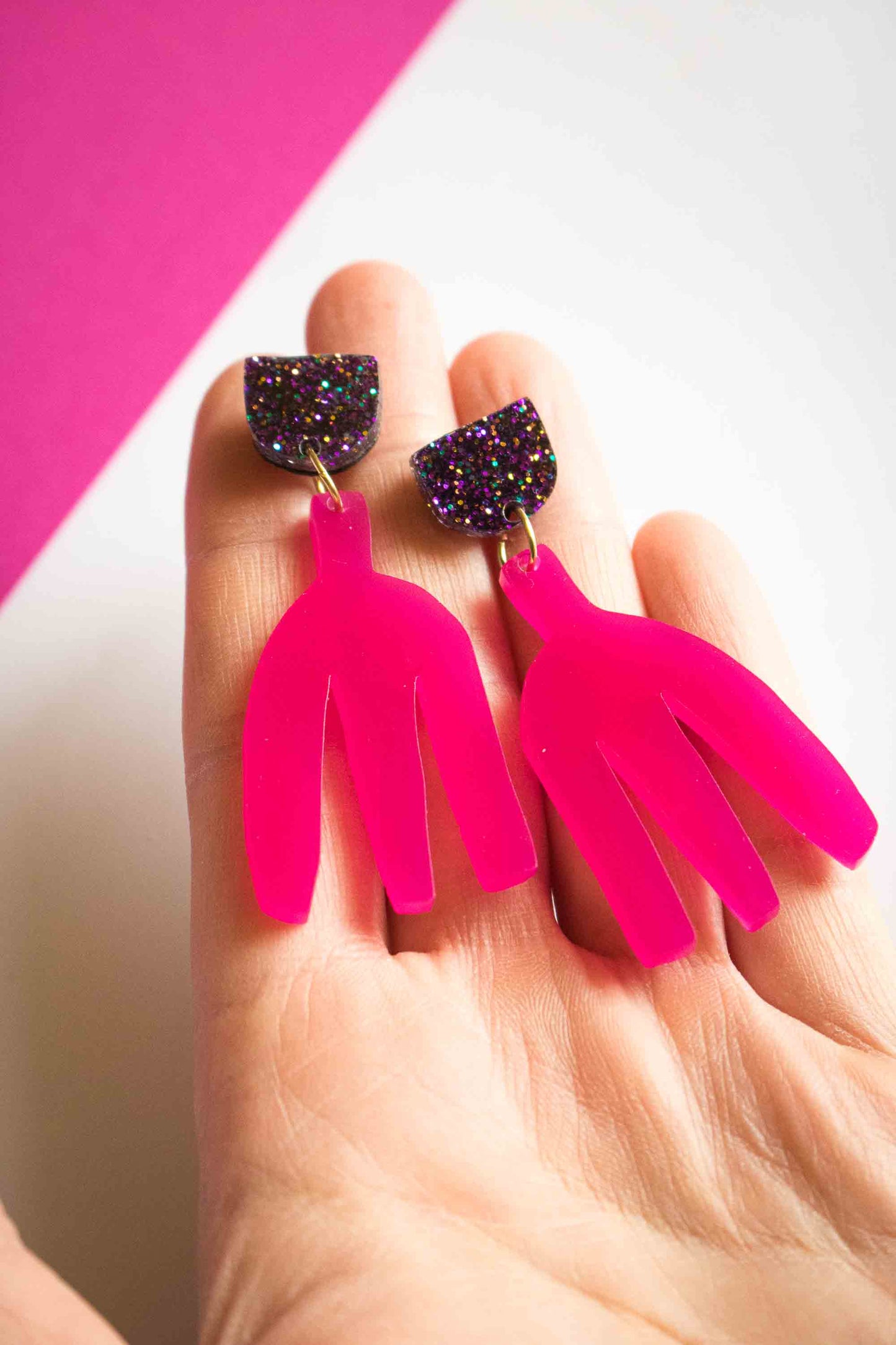 Boucles d'oreilles pendantes fuchsia en acrylique découpé au laser tenues dans la paume, clou pailleté holographique, bijoux faits main Limonade Studio