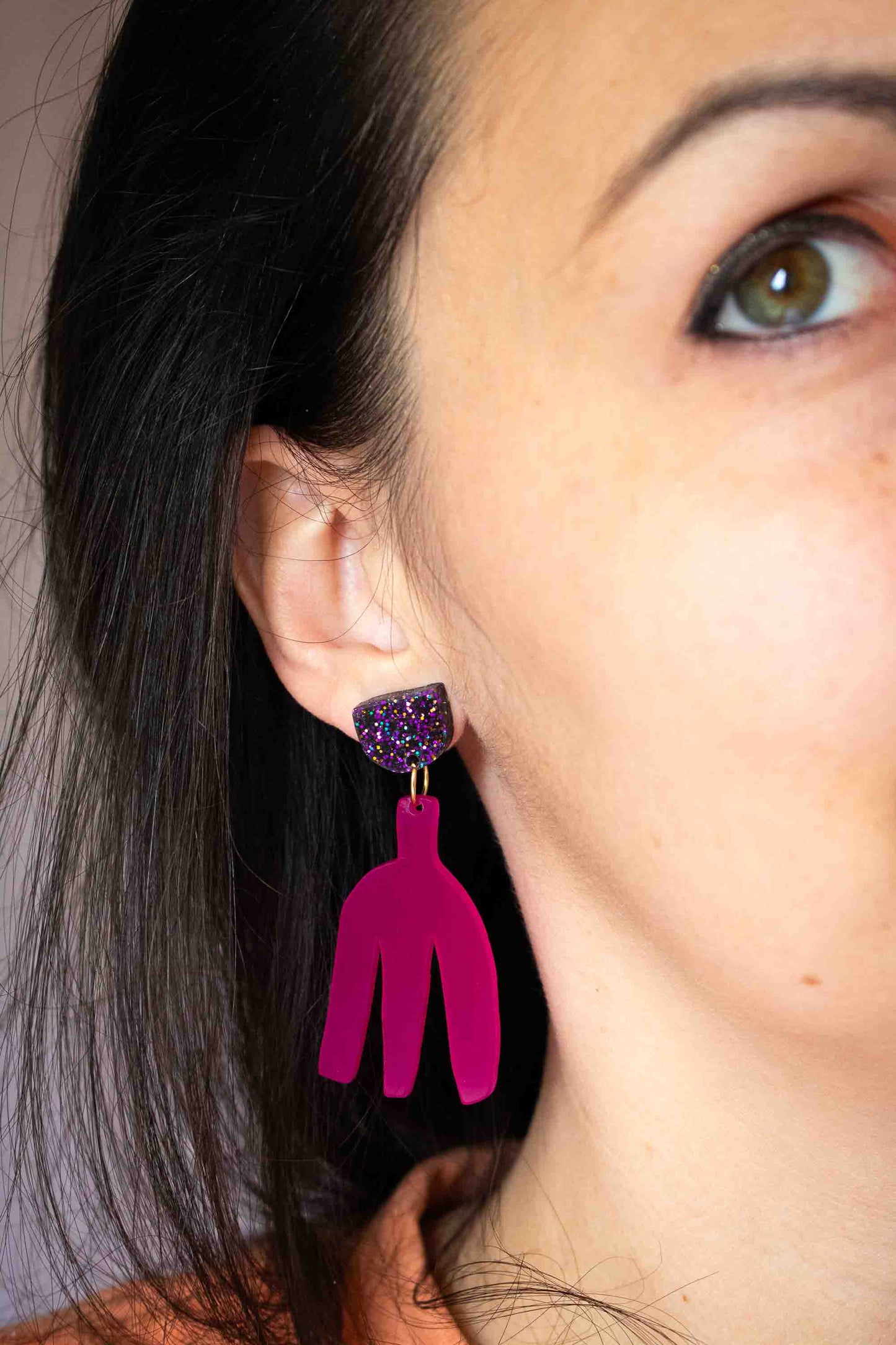 Boucles d'oreilles pendantes fuchsia en acrylique découpé au laser portées, clou pailleté holographique, gros plan sur l'oreille, bijoux faits main Limonade Studio