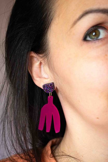 Boucles d'oreilles pendantes fuchsia en acrylique découpé au laser portées, clou pailleté holographique, gros plan sur l'oreille, bijoux faits main Limonade Studio