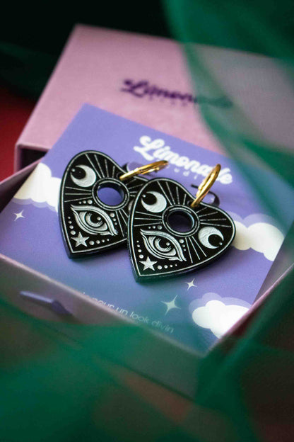 Boucles en forme de planchette Ouija rangées dans un écrin violet ouvert