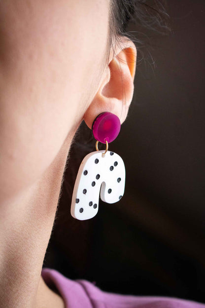 Gros plan boucles d'oreilles acrylique rose et blanc à pois noirs portées sur oreille, Limonade Studio