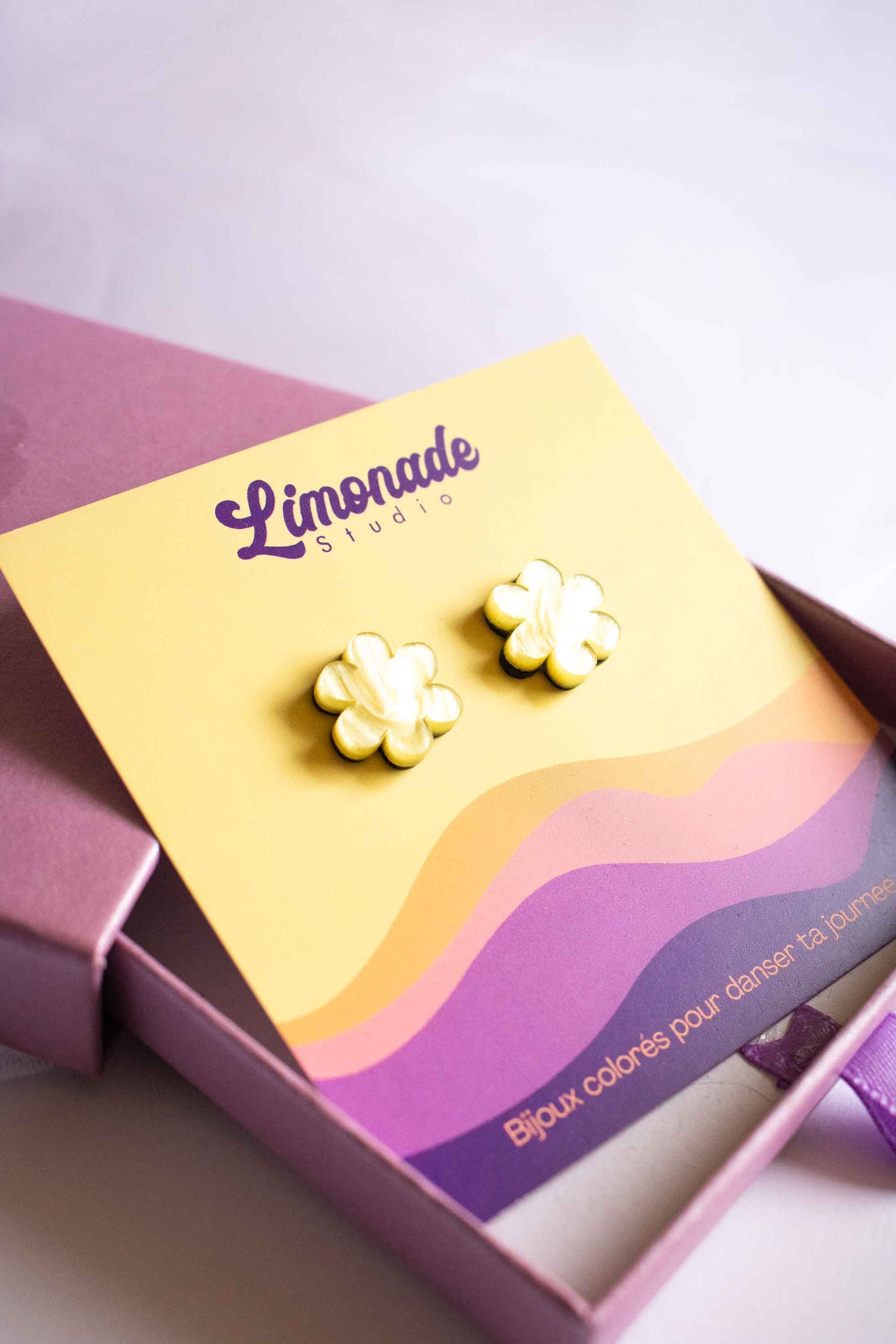 Boucles d'oreilles puces fleur jaune Limonade Studio présentées dans leur boîte cadeau violette
