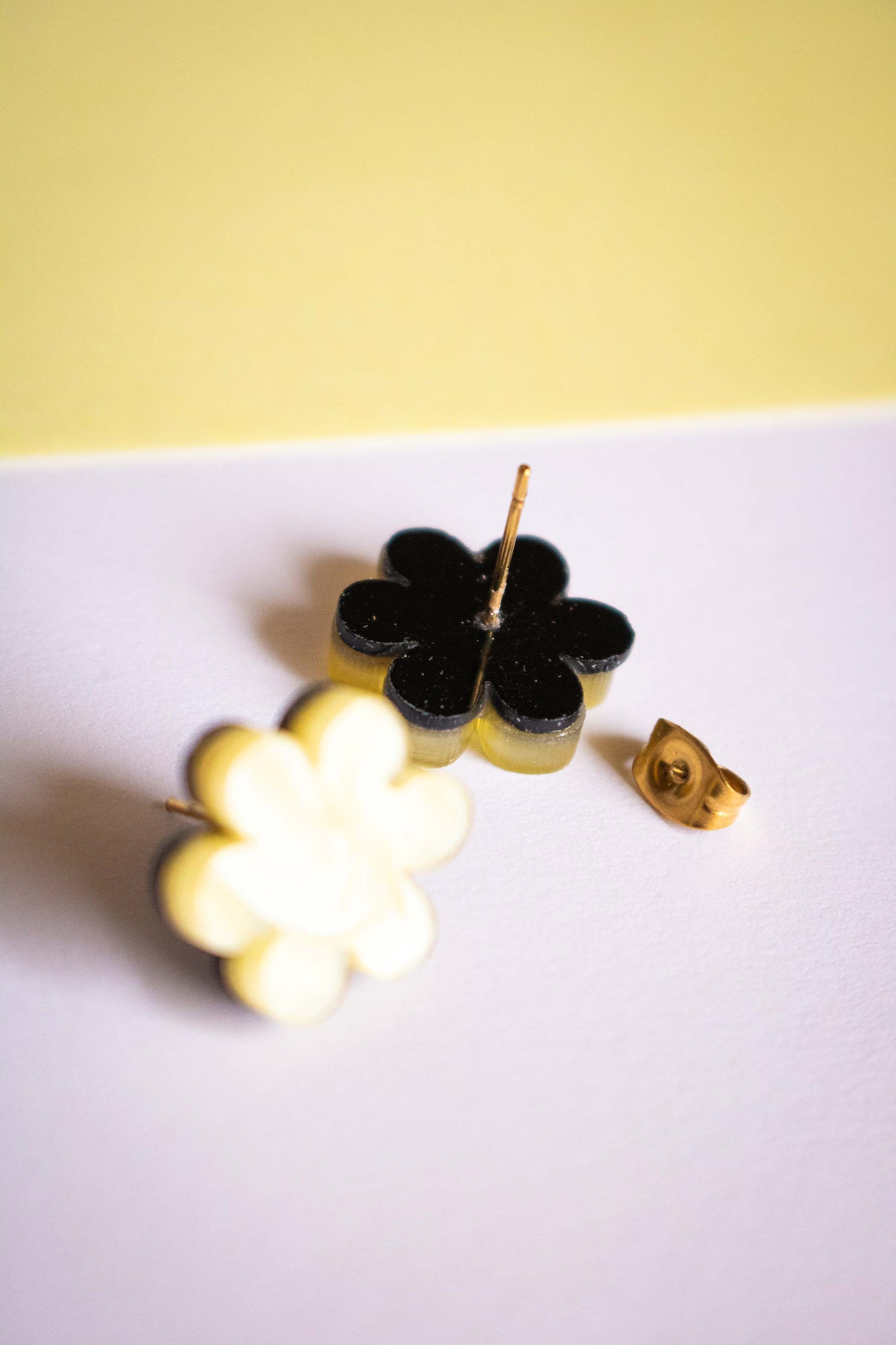 Détail du dos des boucles d'oreilles puces fleur jaune acrylique, tige et poussette dorées en acier inoxydable