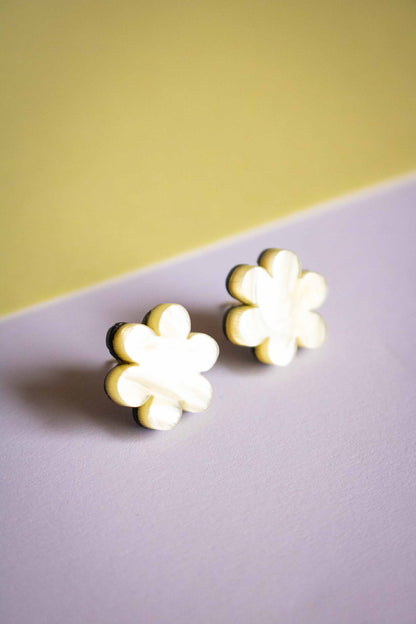 Boucles d'oreilles puces fleur jaune acrylique posées sur fond bicolore jaune et violet, bijoux faits main Limonade Studio