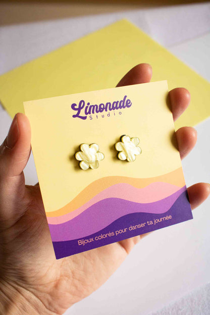 Main tenant la carte d'emballage Limonade Studio avec les puces fleur jaune en acrylique découpé au laser