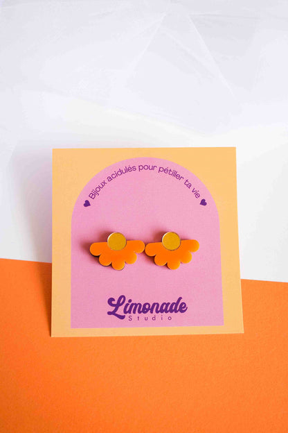 Puces fleur orange en acrylique découpé au laser sur cartonnette Limonade Studio, fond bicolore blanc et orange, cadrage serré
