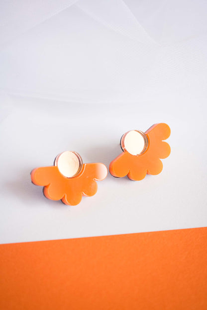 Puces fleur orange en acrylique découpé au laser posées à plat, centre miroir doré, fond bicolore blanc et orange