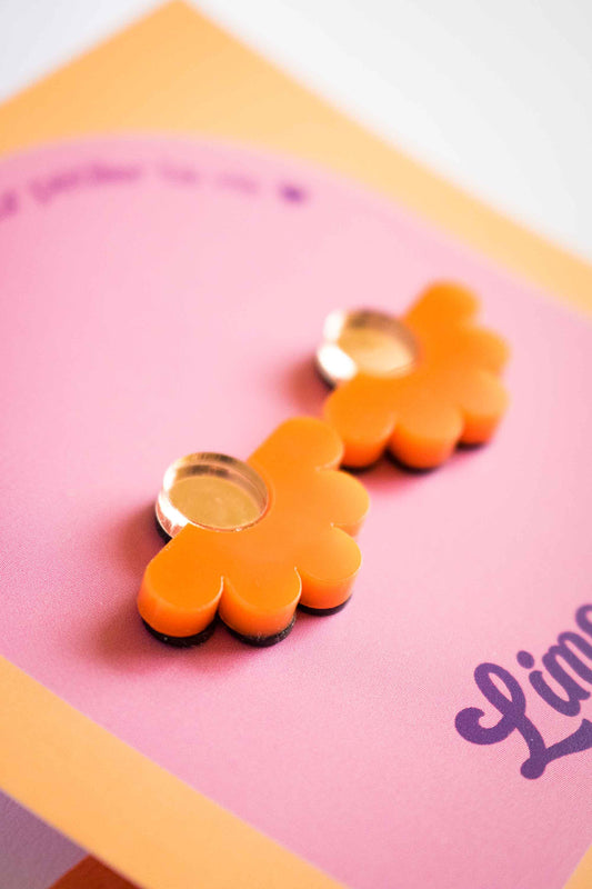 Gros plan sur les puces fleur orange en acrylique découpé au laser, centre miroir doré, texture et reflets, sur cartonnette Limonade Studio
