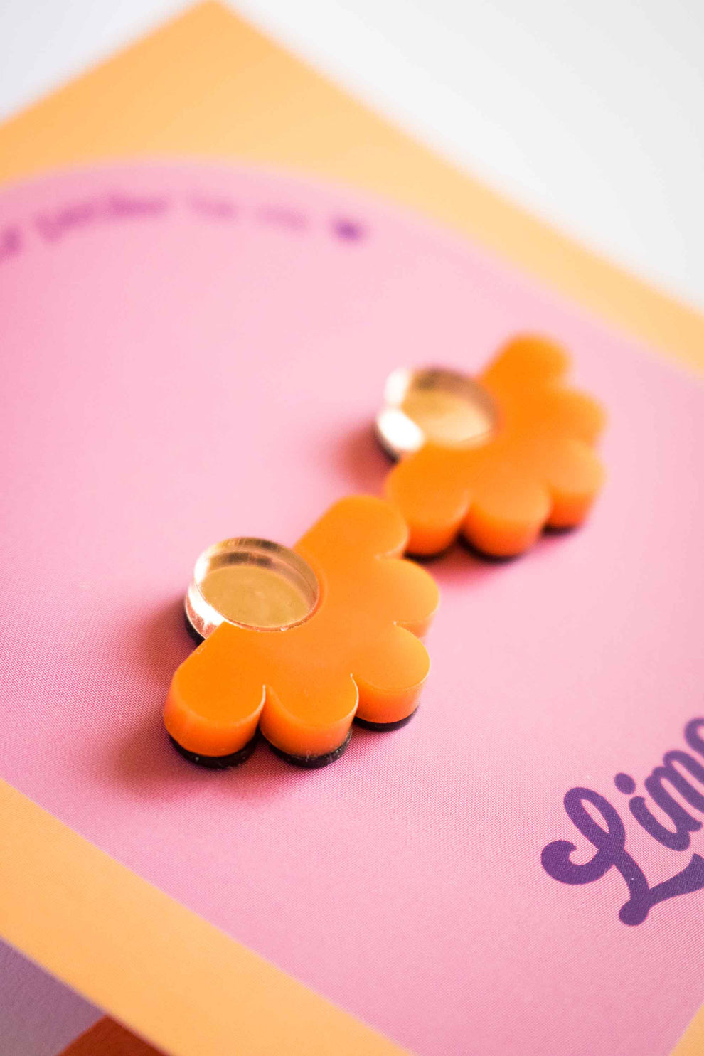 Puces d'oreilles fleur géométrique en acrylique orange vif, centre miroir doré, clou plaqué or 18 carats. Bijou coloré et audacieux, Limonade Studio.