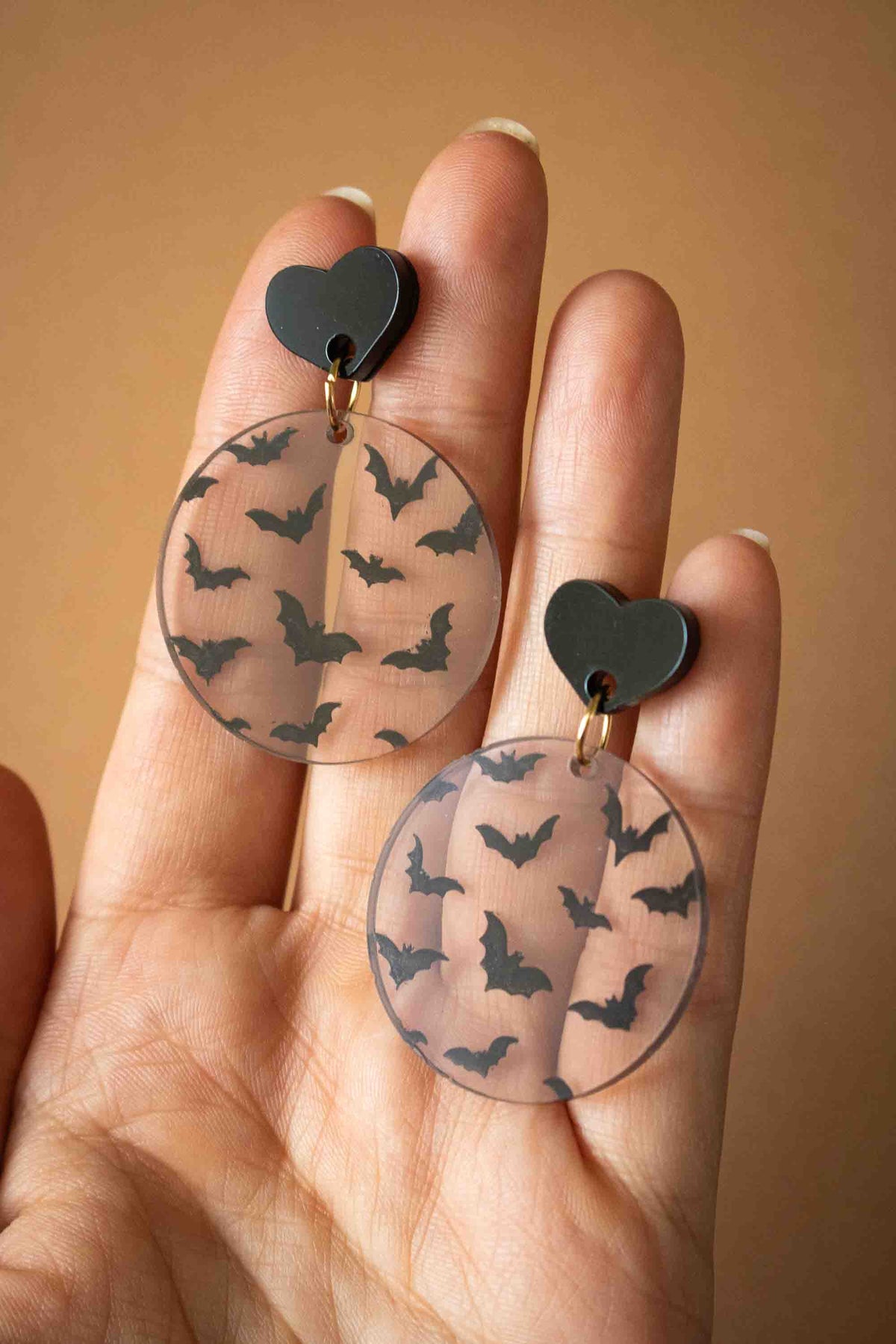 Boucles d’oreilles rondes chauves-souris présentées dans une main pour montrer leur taille