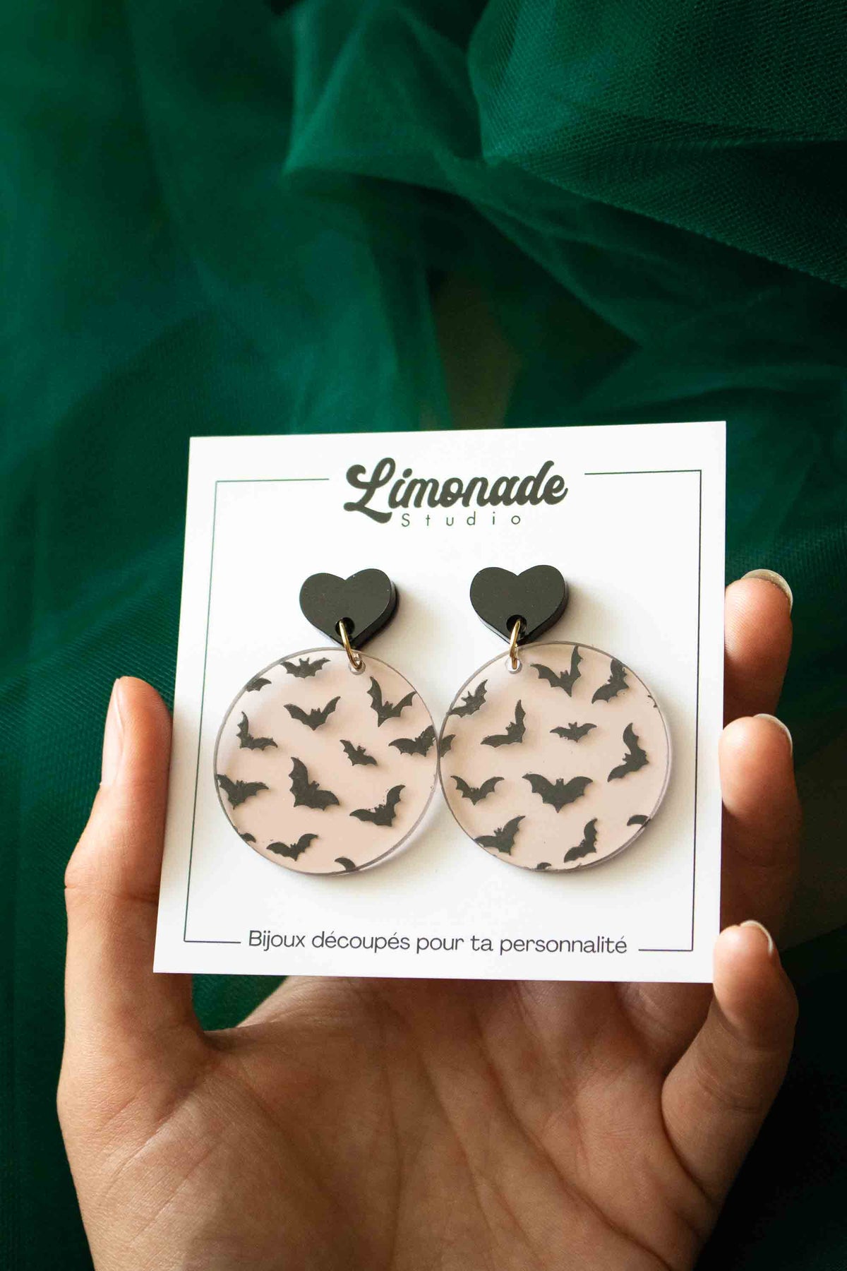 Boucles d’oreilles chauves-souris sur leur carte Limonade Studio tenue dans une main