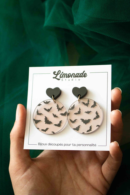 Boucles d’oreilles chauves-souris sur leur carte Limonade Studio tenue dans une main