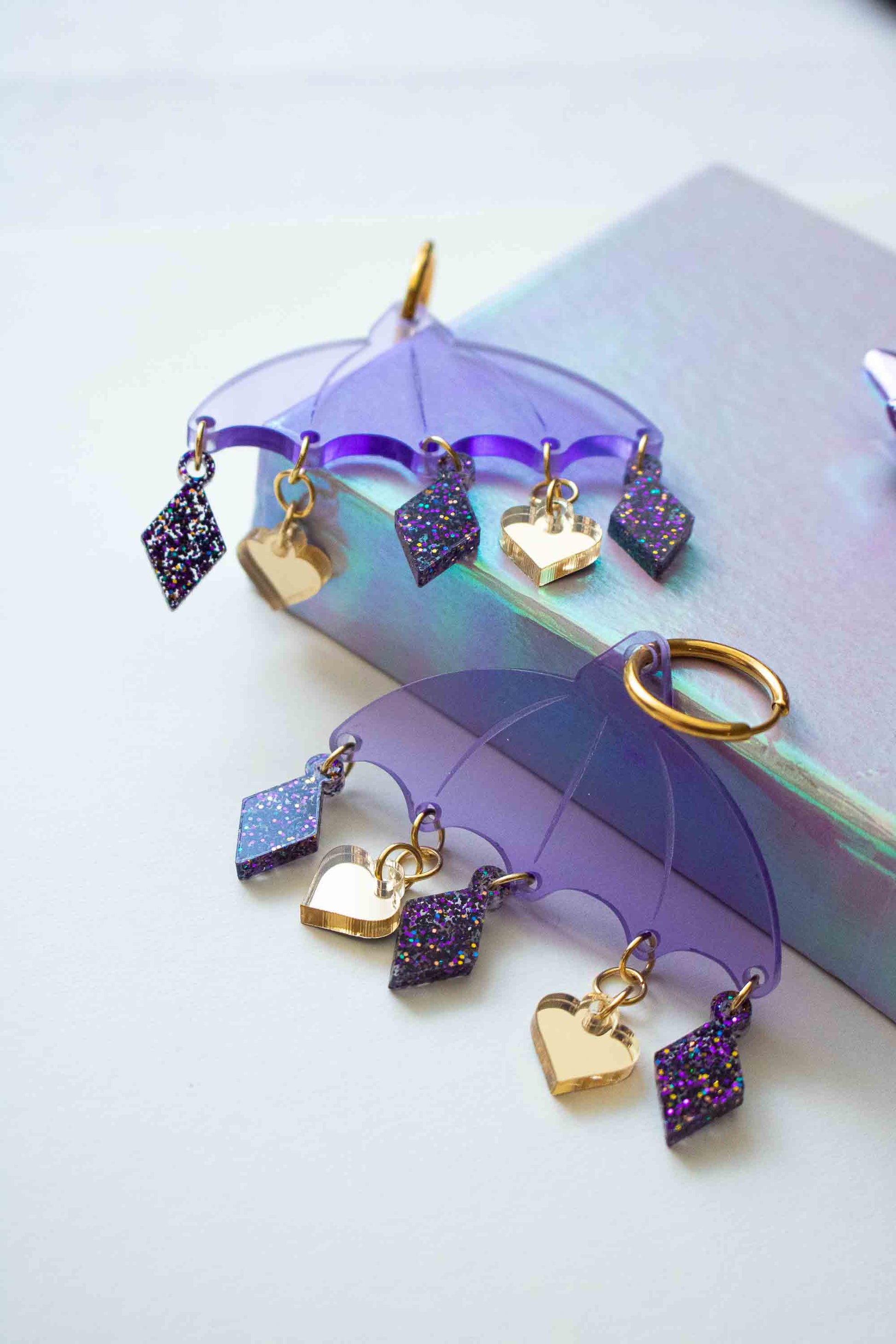 Boucles d'oreilles violettes en acrylique decoupe laser, bijou createur Limonade Studio, posees simplement dans un decor doux et lumineux.