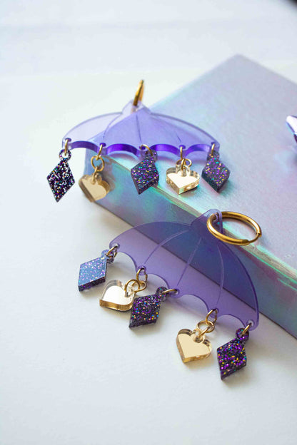 Boucles d'oreilles violettes en acrylique decoupe laser, bijou createur Limonade Studio, posees simplement dans un decor doux et lumineux.