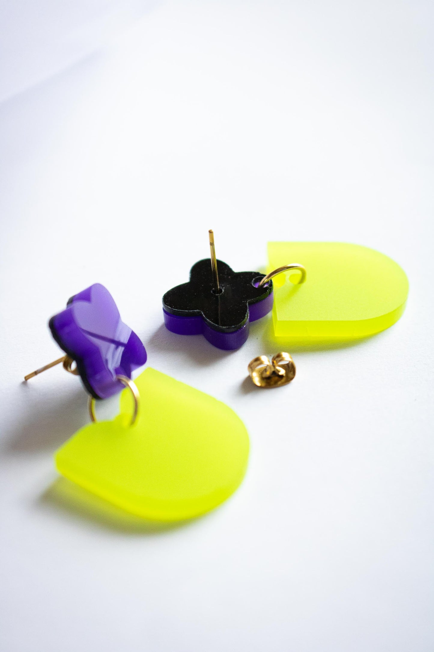 Dos des boucles pendantes fleur violette vert acrylique fait main Limonade Studio, détail tiges acier et anneaux dorés, fond blanc
