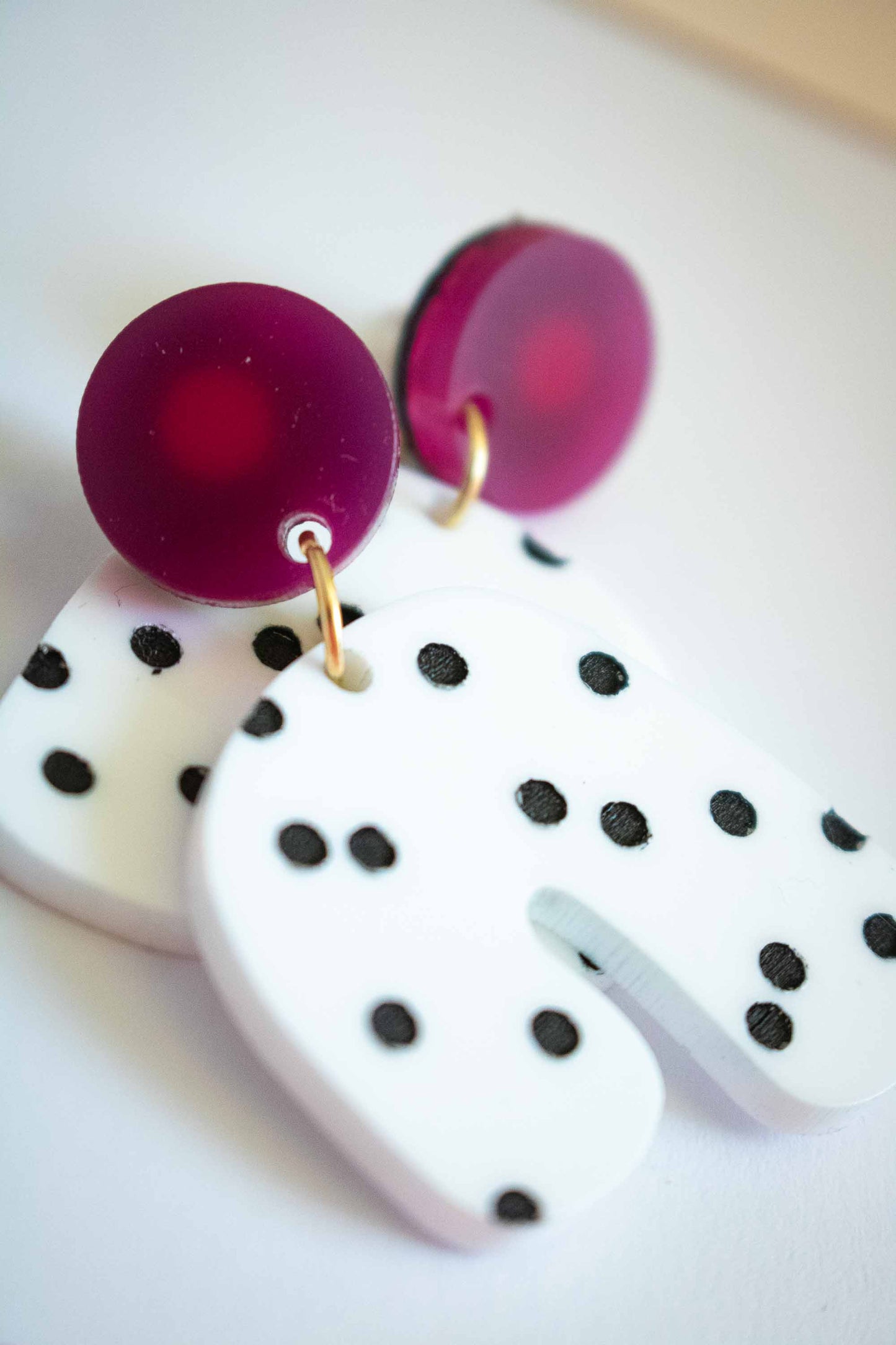 Gros plan boucles d'oreilles acrylique blanc à pois noirs et rond rose foncé, Limonade Studio