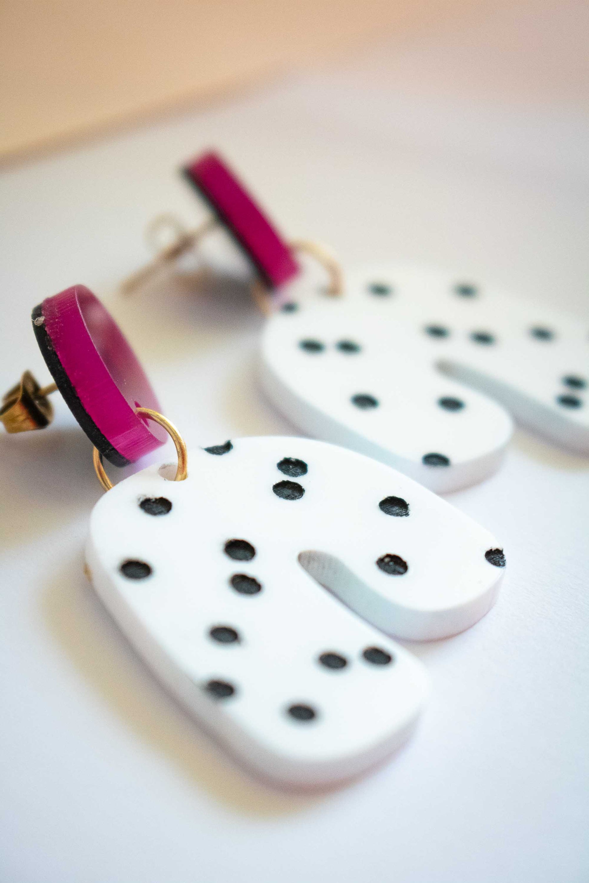 Gros plan boucles d'oreilles acrylique blanc à pois noirs et rond rose foncé, Limonade Studio