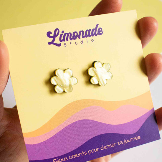 Vidéo des boucles puces jaunes en forme de fleur en acrylique découpé au laser Limonade Studio, portées à l'oreille et présentées dans leur boîte cadeau violette, bijou fantaisie fait main