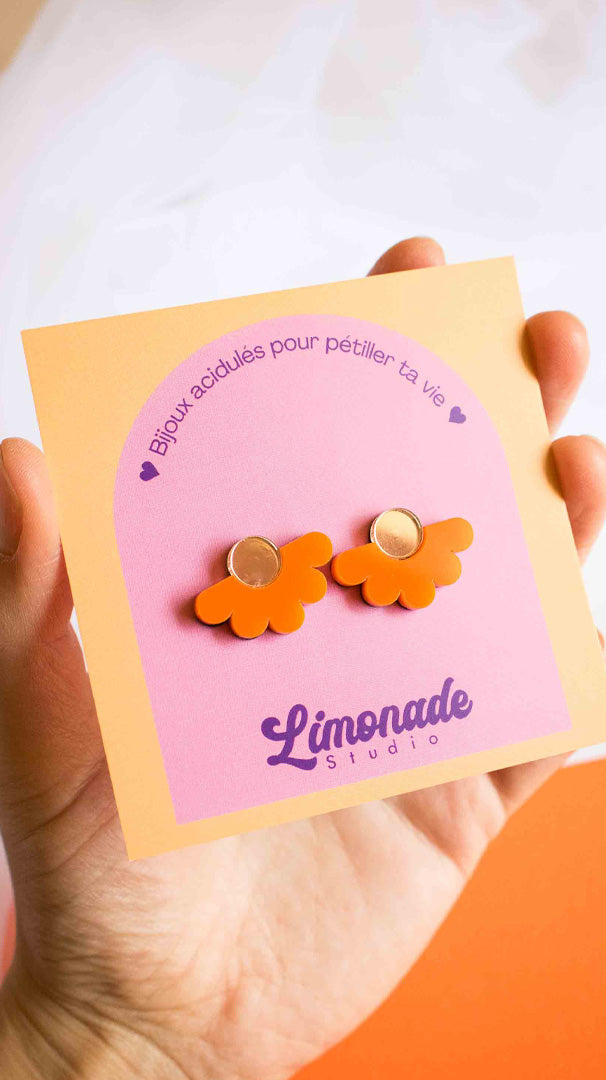 Vidéo des boucles d'oreilles puces fleur orange en acrylique découpé au laser Limonade Studio : vue portée puis présentées sur leur cartonnette d'emballage, bijoux faits main colorés