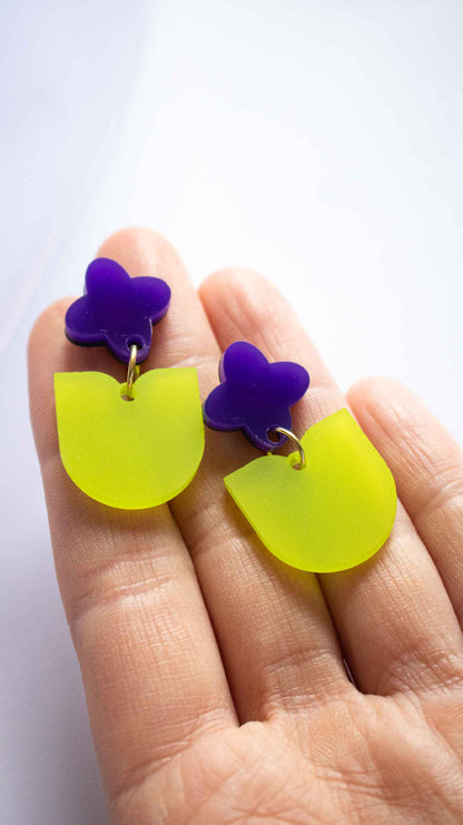 Boucles d'oreilles pendantes fleur violette et feuille verte acrylique dépoli, fait main découpe laser Limonade Studio, portées et présentées avec packaging
